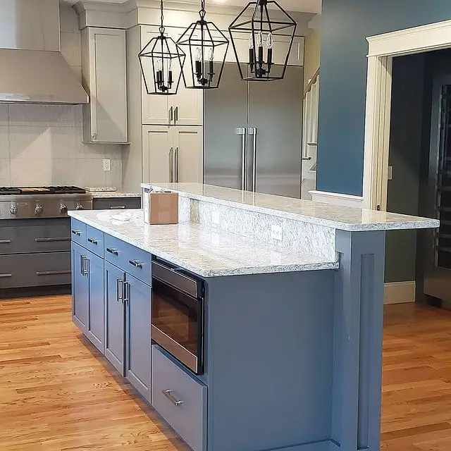 Modern kitchen design featuring blue cabinetry, granite countertop, stainless steel appliances, and pendant lighting, illustrating Seacoast Cabinet's renovation expertise.