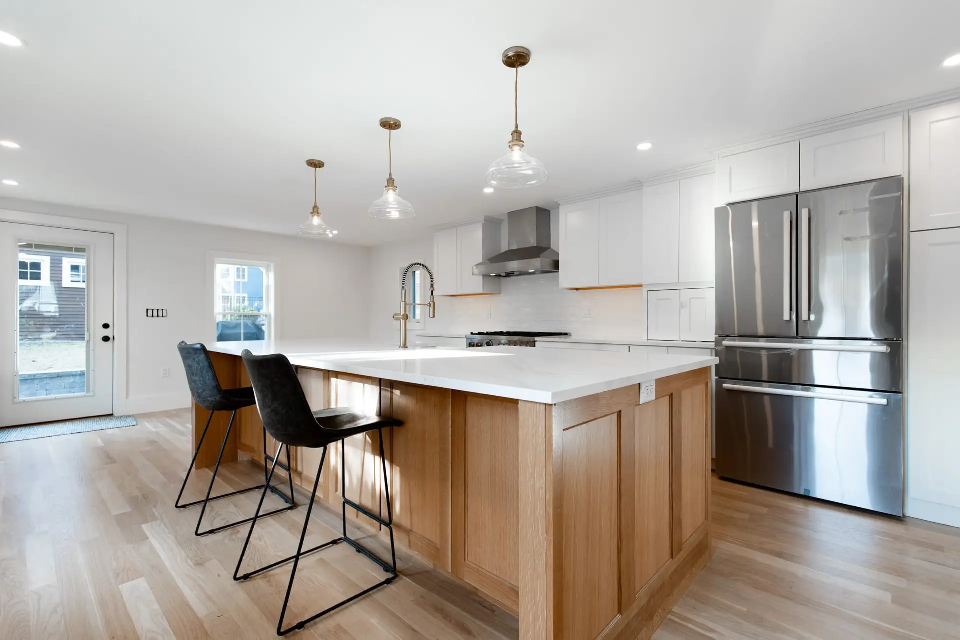 34B Woodland St-19 Modern kitchen featuring durable white cabinetry, stainless steel appliances, and a spacious island with wooden accents, illuminated by pendant lights, ideal for kitchen remodeling.