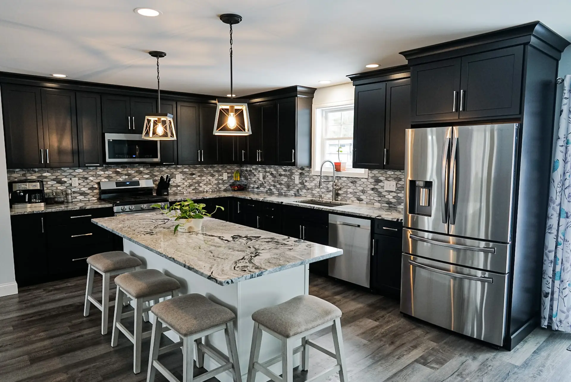 Modern kitchen featuring dark cabinetry, stainless steel appliances, granite countertop island with seating, and stylish pendant lighting, showcasing Seacoast Cabinet's design expertise for Haverhill homeowners.